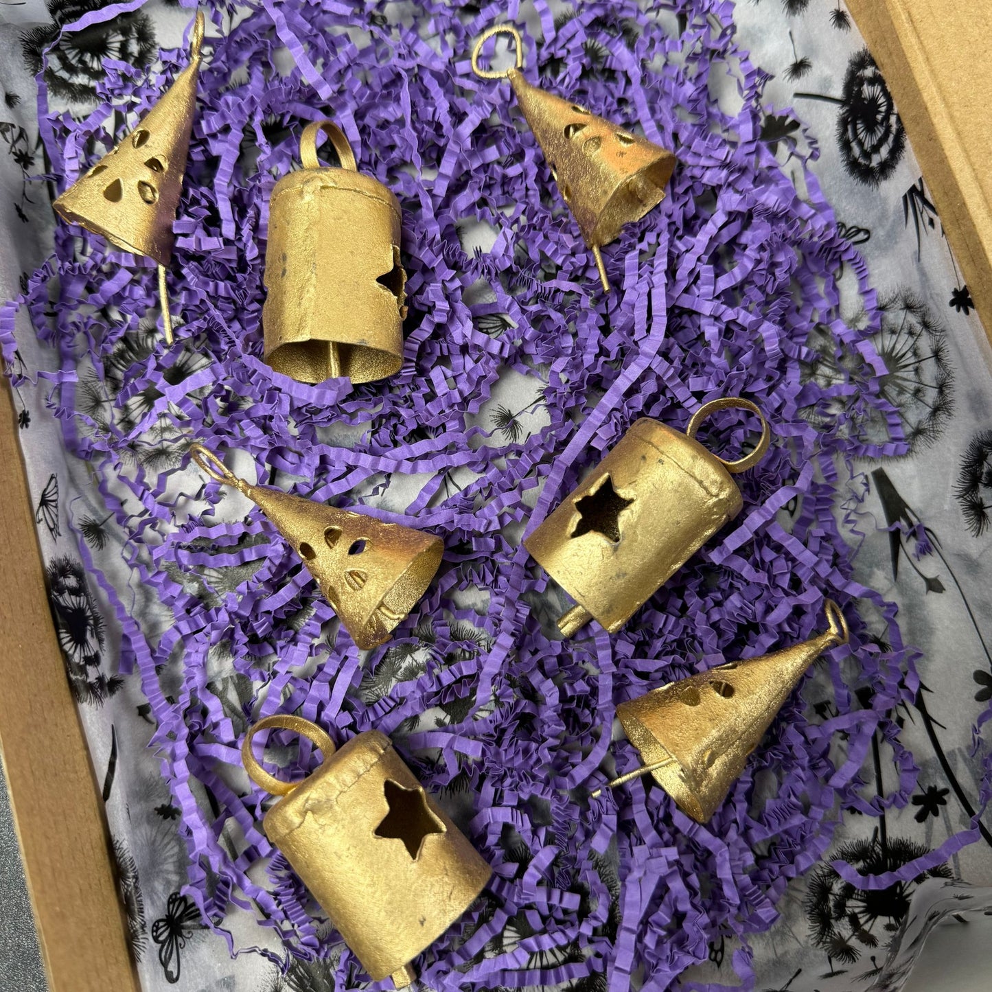Gold bells with star designs on purple shredded paper